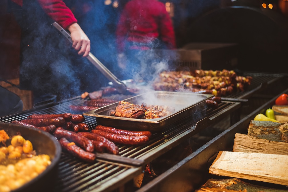 BBQ grill covered in meats as someone cooks